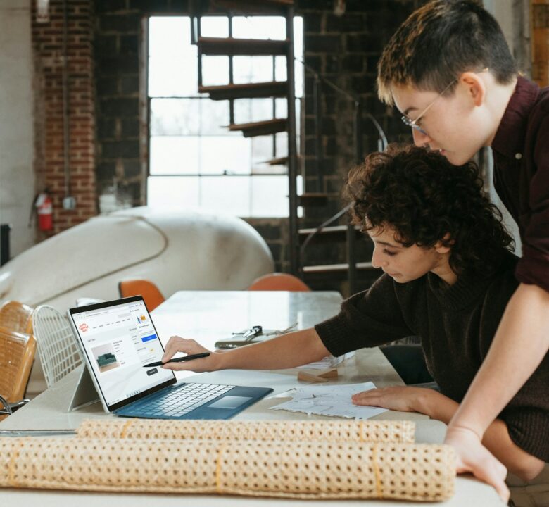 a man and a woman are looking at a laptop