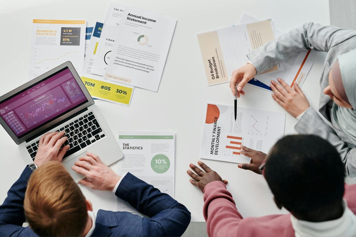 Business meeting with professionals discussing financial reports and graphs at a work desk.